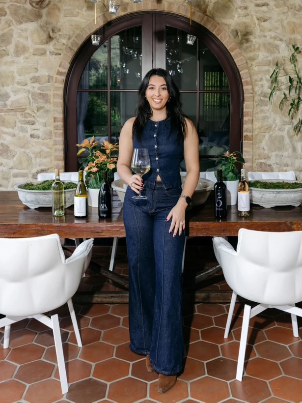 Amanda Rubin with a glass of wine at a long table on the estate terrace