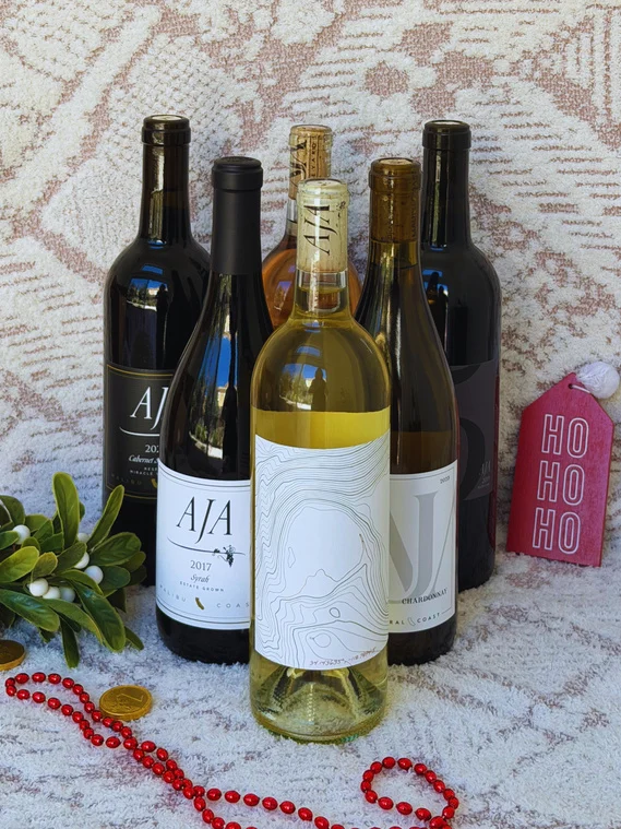 Six AJA wines arranged on a holiday blanket with a red gift tag