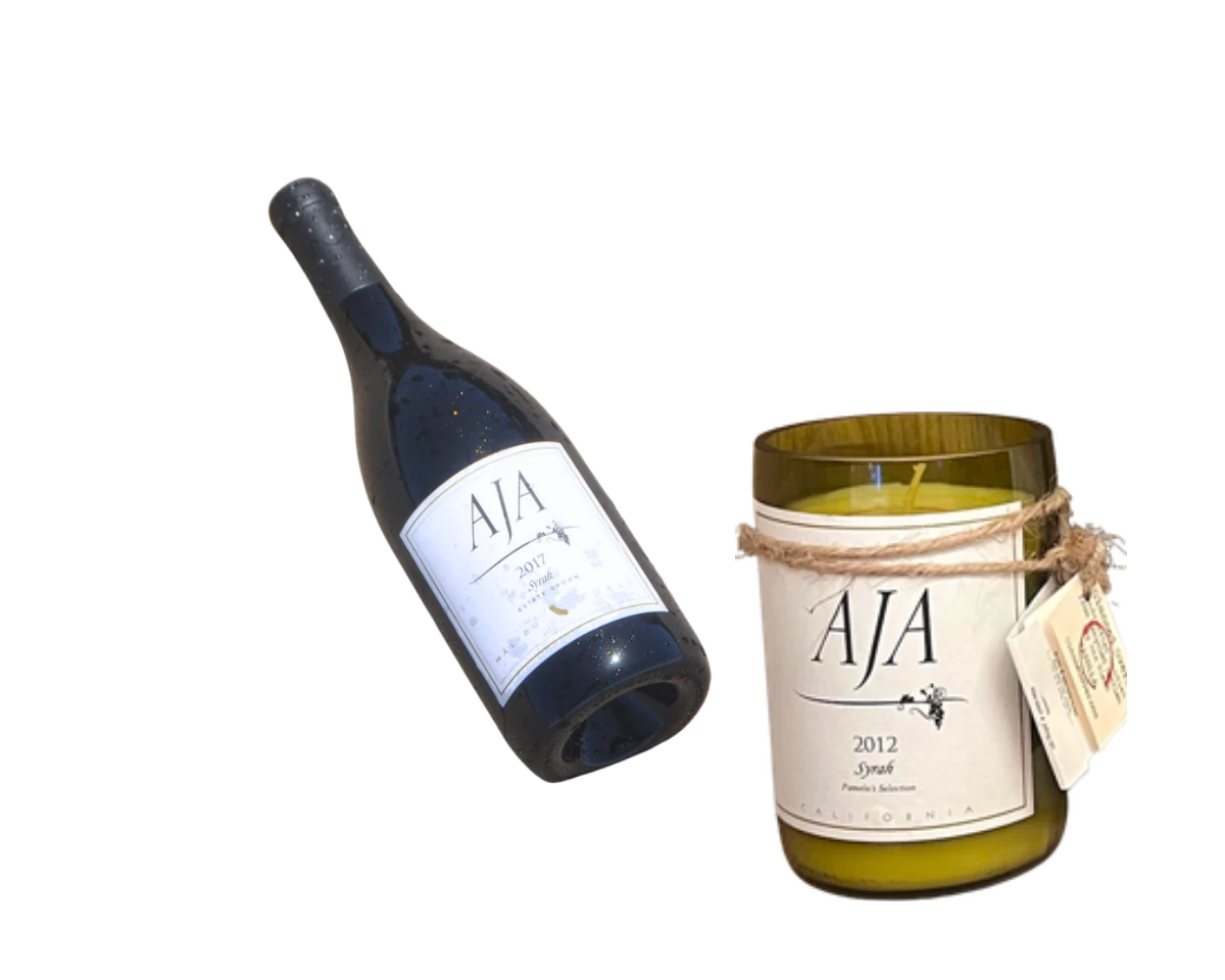 A bottle of AJA Syrah beside an AJA Syrah Vanilla upcycled candle