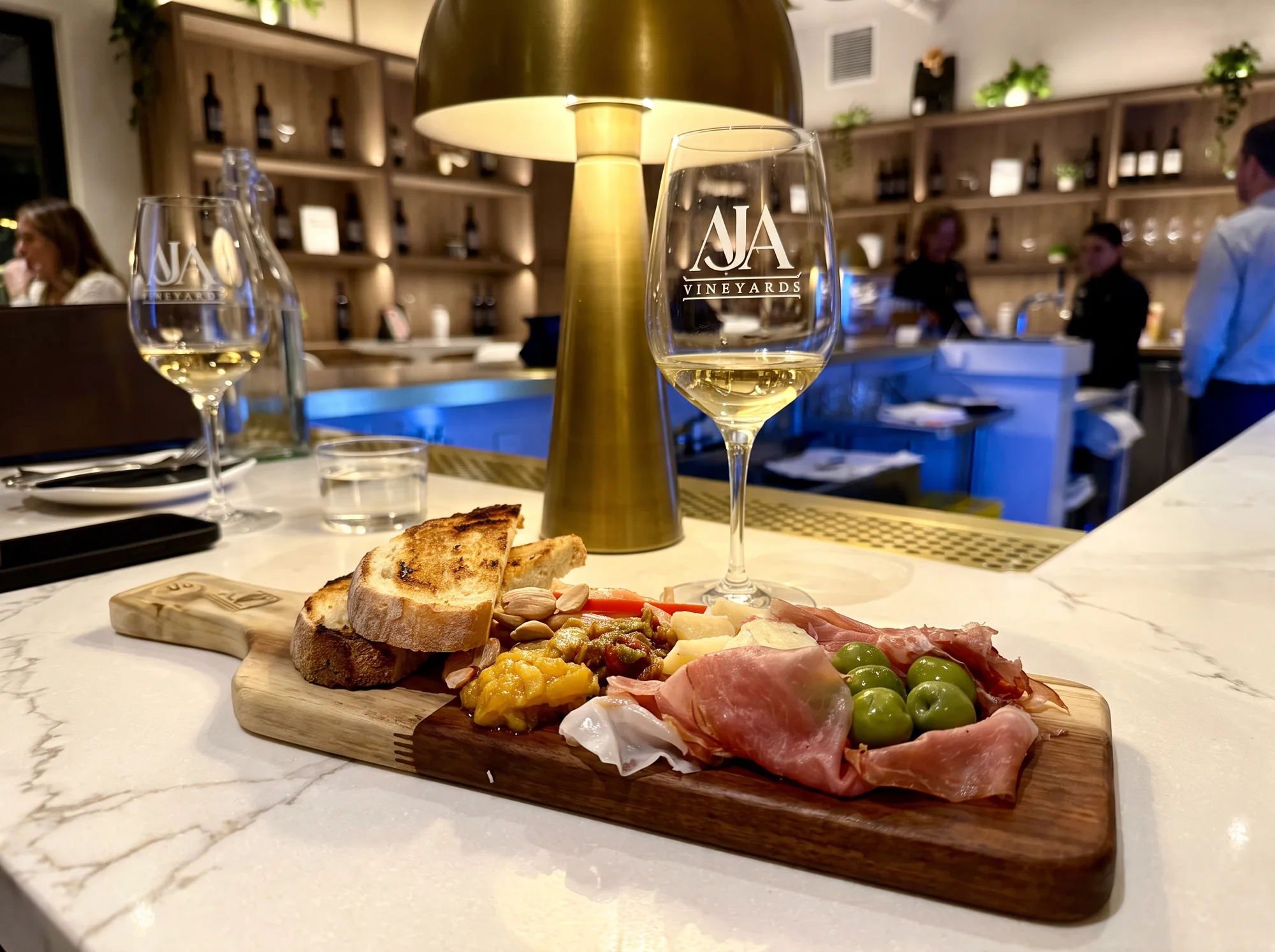 A charcuterie board of cured meats and cheeses alongside glasses of AJA wine